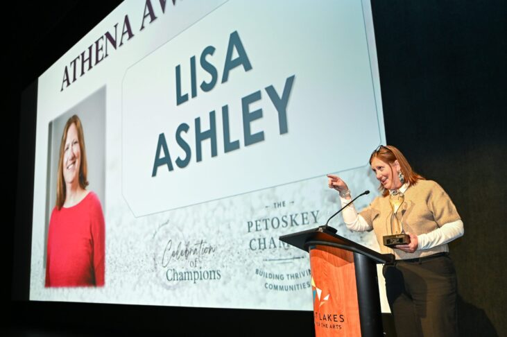 Lisa Ashley at podium to receive award with her photo on screen behind her
